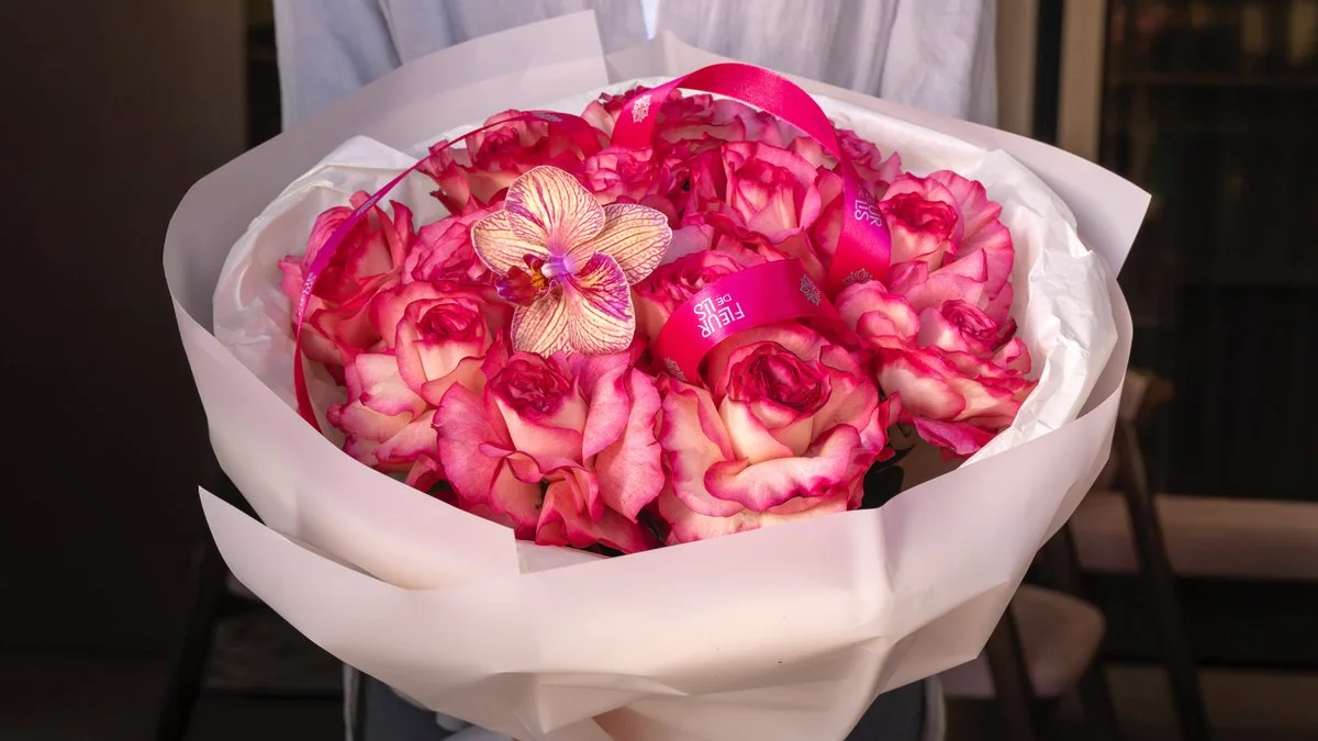 «Pure Allure» — круглый букет алых и розовых роз с орхидеей